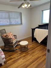 Bedroom with wood finished floors, a textured ceiling, baseboards, and ceiling fan