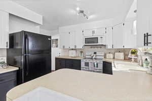 Kitchen featuring white cabinetry, white appliances, light countertops, and decorative backsplash