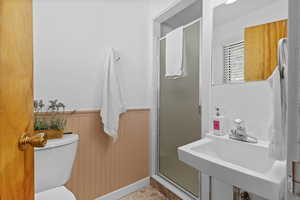 Bathroom with a shower stall, wainscoting, and wood walls