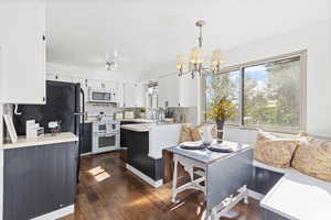 Kitchen featuring healthy amount of natural light, backsplash, light countertops, and white appliances
