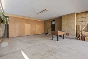 Below grade area with brick wall, a textured ceiling, and wooden walls