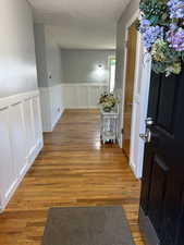 Corridor featuring a decorative wall, a wainscoted wall, wood finished floors, and a textured ceiling