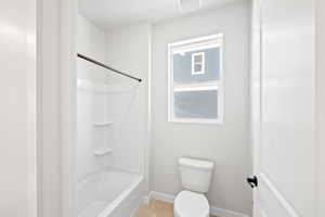Full bath featuring tub / shower combination, visible vents, baseboards, and toilet