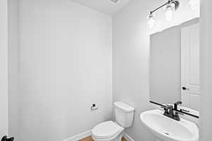 Bathroom featuring wood finished floors, toilet, baseboards, and a sink