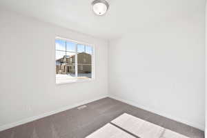 Empty room featuring carpet flooring, visible vents, and baseboards