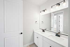Full bath with a sink, baseboards, double vanity, and tile patterned floors