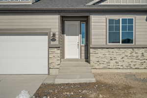 Entrance to property with a garage and roof with shingles