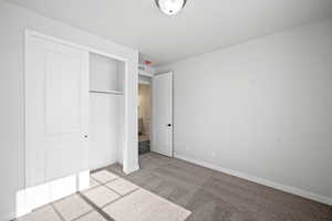 Unfurnished bedroom featuring a closet, visible vents, light colored carpet, and baseboards