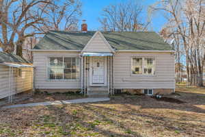 Bungalow-style home with fence, roof with shingles, and a chimney