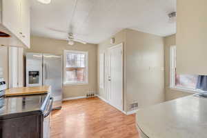 Kitchen with light wood-type flooring, baseboards, visible vents, and range with electric stovetop