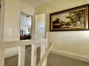 Corridor featuring baseboards and carpet flooring