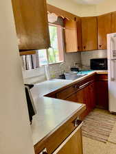 Kitchen featuring freestanding refrigerator, a sink, light countertops, black microwave, and tasteful backsplash