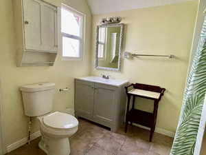 Bathroom with tile patterned floors, baseboards, vanity, and toilet