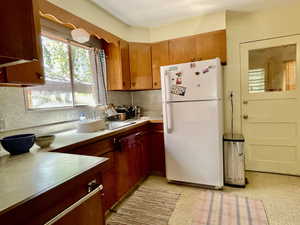 Kitchen featuring light countertops, freestanding refrigerator, light floors, and a sink