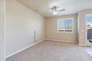 Empty room featuring a textured ceiling, a ceiling fan, baseboards, visible vents, and light carpet