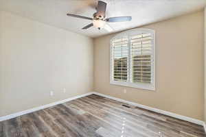 Spare room with a textured ceiling, wood finished floors, baseboards, and ceiling fan