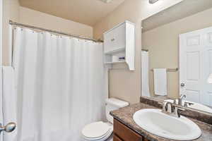 Full bathroom with curtained shower, a textured ceiling, toilet, and vanity