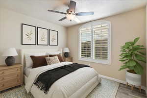 Bedroom with a textured ceiling, a ceiling fan, baseboards, and wood finished floors**Please note this is virtually staged**