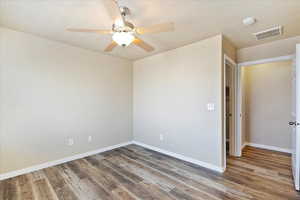 Empty room featuring visible vents, baseboards, a textured ceiling, and wood finished floors