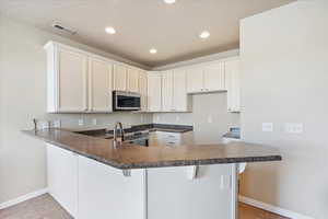 Kitchen featuring dark countertops, visible vents, light tile patterned floors, a peninsula, and stainless steel appliances