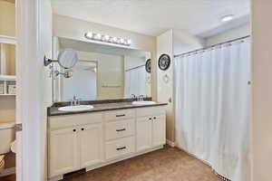 Bathroom featuring a textured ceiling, toilet, visible vents, and a sink