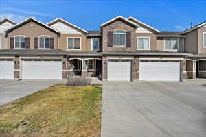 Townhome / multi-family property featuring stone siding, a garage, driveway, and stucco siding