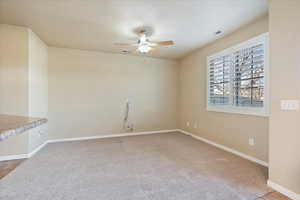 Carpeted empty room featuring baseboards, visible vents, a textured ceiling, and a ceiling fan