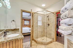 Ensuite Primary Bathroom with vanity, ensuite bath, stone tile flooring, and a shower stall