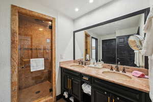 Full bathroom featuring a textured wall, a stall shower, and a sink