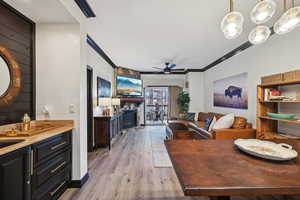 Dining area featuring ceiling fan, light wood-style floors, ornamental molding, and a fireplace