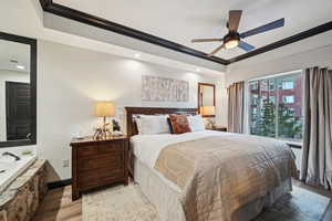 Bedroom with crown molding, a textured wall, visible vents, and light wood finished floors