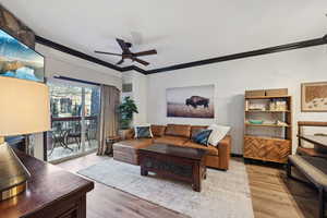 Living area featuring ceiling fan, wood finished floors, and crown molding