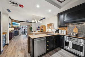 Kitchen with visible vents, a sink, appliances with stainless steel finishes, a peninsula, and decorative backsplash