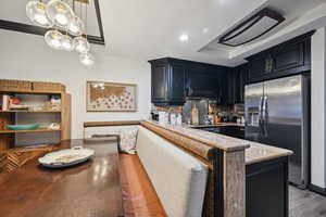 Kitchen featuring recessed lighting, custom range hood, black electric cooktop, stainless steel fridge, and backsplash