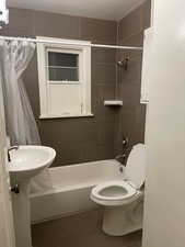 Bathroom featuring toilet and shower / tub combo with curtain