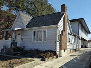 View of front facade featuring roof with shingles and a chimney