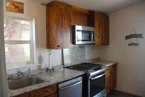 Kitchen with plenty of natural light, brown cabinetry, appliances with stainless steel finishes, and a sink