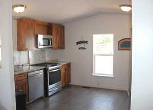 Kitchen featuring brown cabinetry, dark wood-style flooring, and stainless steel appliances