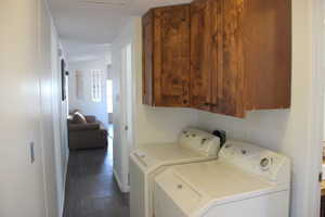 Washroom with washer and clothes dryer, cabinet space, and dark wood-style flooring