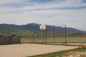 View of sport court featuring a mountain view, a rural view, community basketball court, and fence
