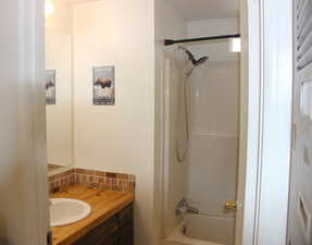 Full bath featuring decorative backsplash, vanity, and shower / bathing tub combination