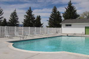 Community pool with a patio and fence