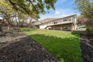 Back of property with stairway, a yard, fence, and a wooden deck