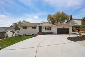 Ranch-style home with a chimney, a front yard, fence, concrete driveway, and an attached garage