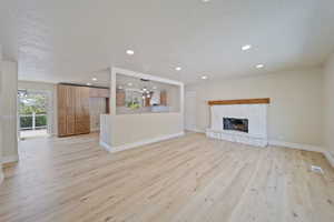 Unfurnished living room with baseboards, light wood-style flooring, a textured ceiling, and a notable chandelier
