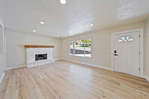 Unfurnished living room with a healthy amount of sunlight, light wood finished floors, and a textured ceiling