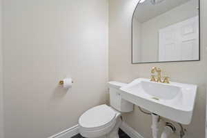 Half bath featuring a sink, baseboards, and toilet