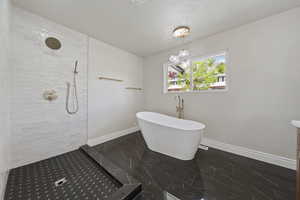 Full bath with a tile shower, a textured ceiling, marble finish floor, baseboards, and a freestanding tub