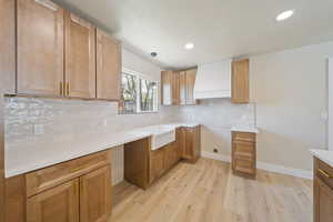 Kitchen featuring backsplash, recessed lighting, custom exhaust hood, and light wood-style flooring