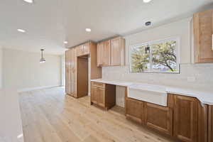 Kitchen with pendant lighting, tasteful backsplash, light wood-type flooring, light countertops, and recessed lighting